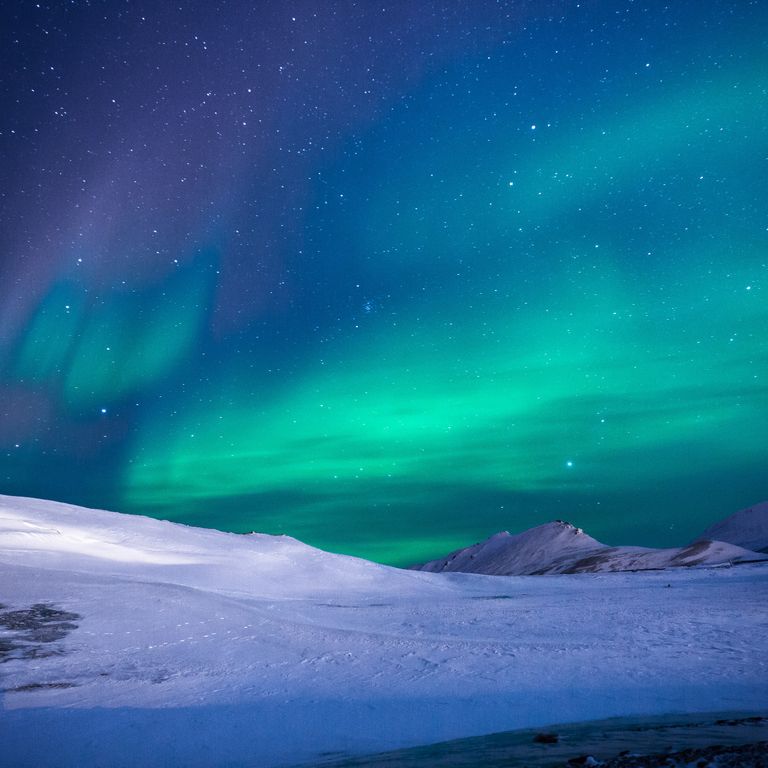 Nordlichter, Sterne, kosmische Energie, schneebedeckte Berge